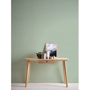 Grüne, leicht strukturierte Vliestapete Uni Matt FSC® an Wand hinter Tisch mit Deko.