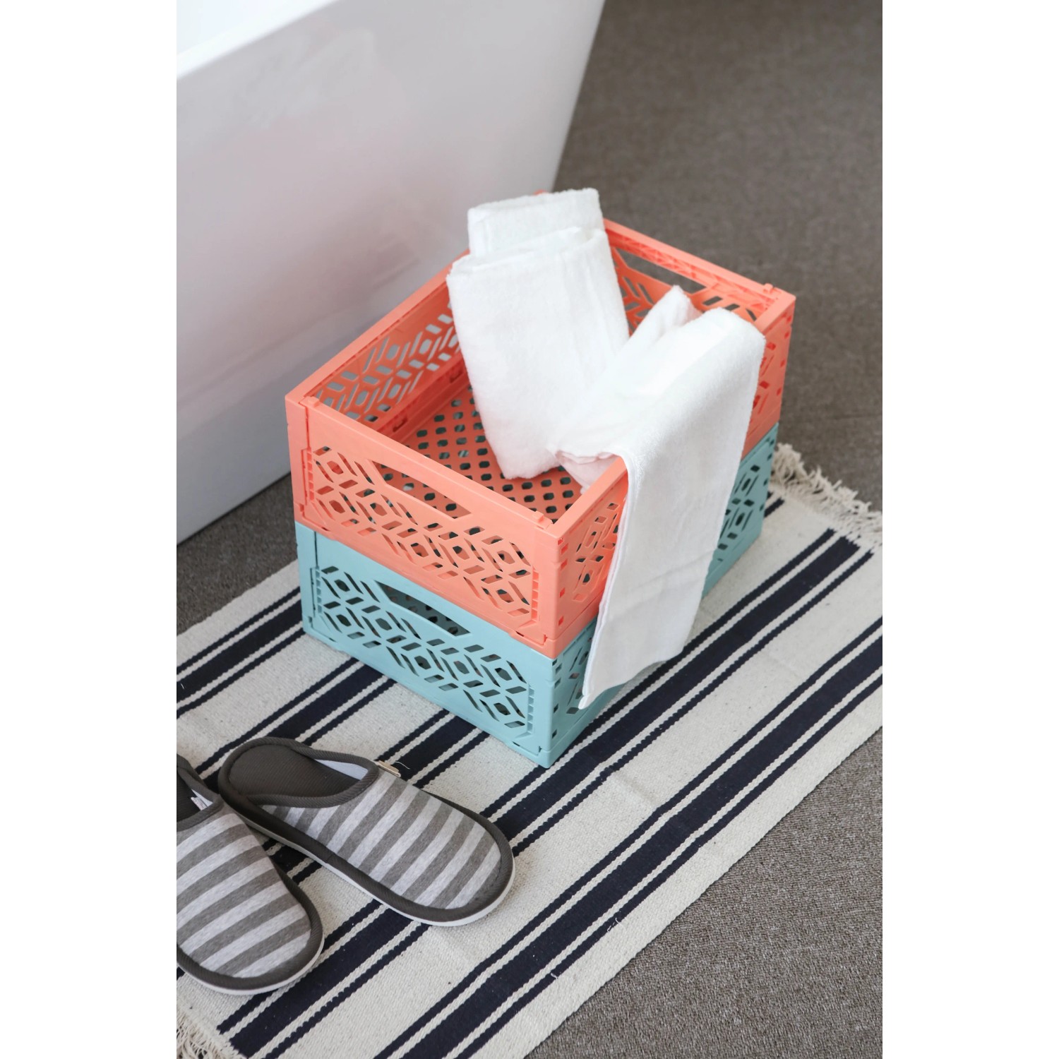Zwei gestapelte Klappboxen Midi (türkis, orange) mit Handtüchern auf einem gestreiften Teppich.