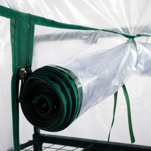 Detailaufnahme: Aufgerolltes Rollo des transparenten KARAT Gewächshauses Casabella mit grüner Umrandung.