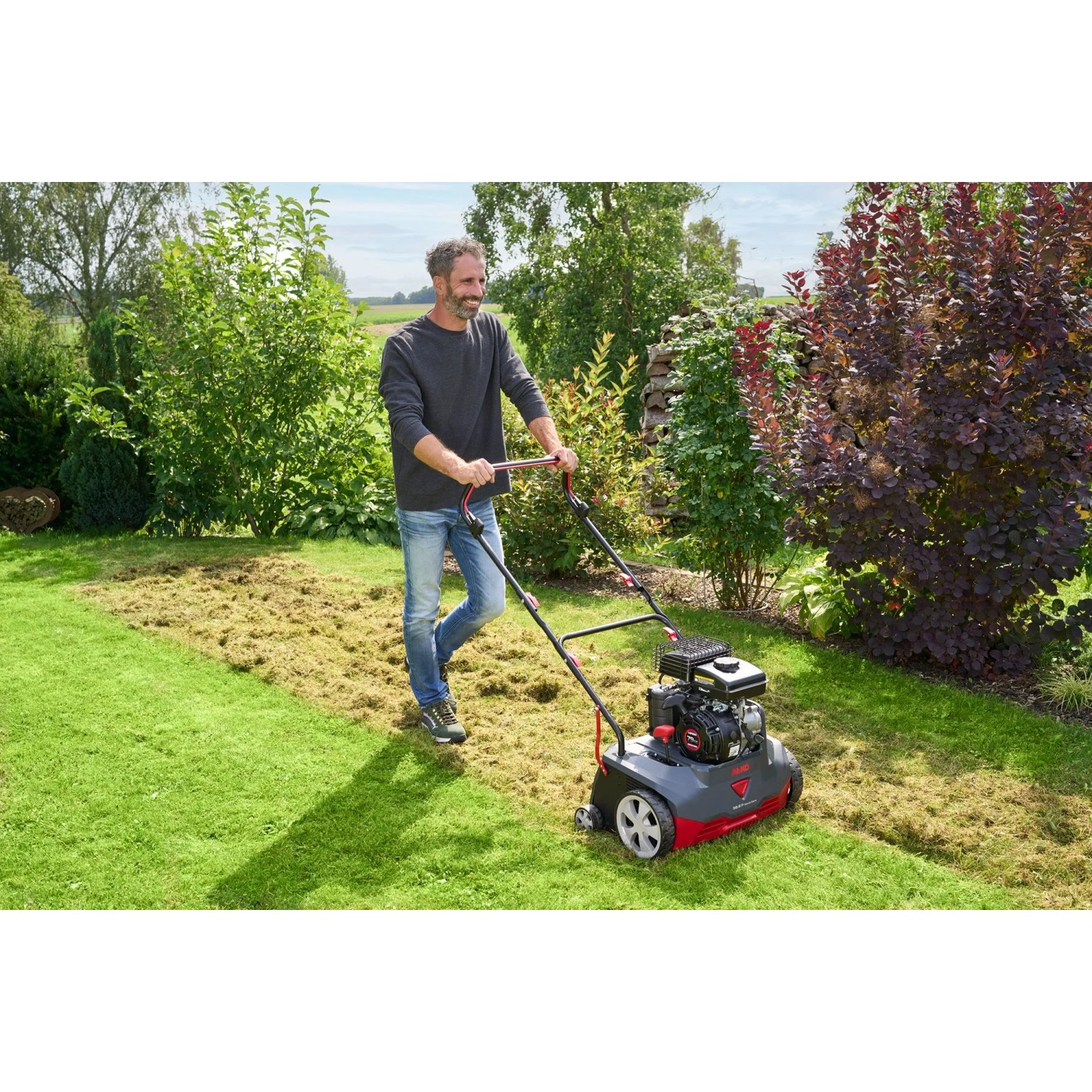 Mann vertikutiert Rasen mit Al-Ko Benzin-Vertikutierer 38.6 P Combi Care Comfort im Garten.