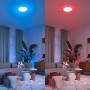 Modernes Wohnzimmer mit smarter Deckenleuchte, die blaues und rotes Licht zeigt. Steuerung mit Philips Smart-Dial-Schalter.