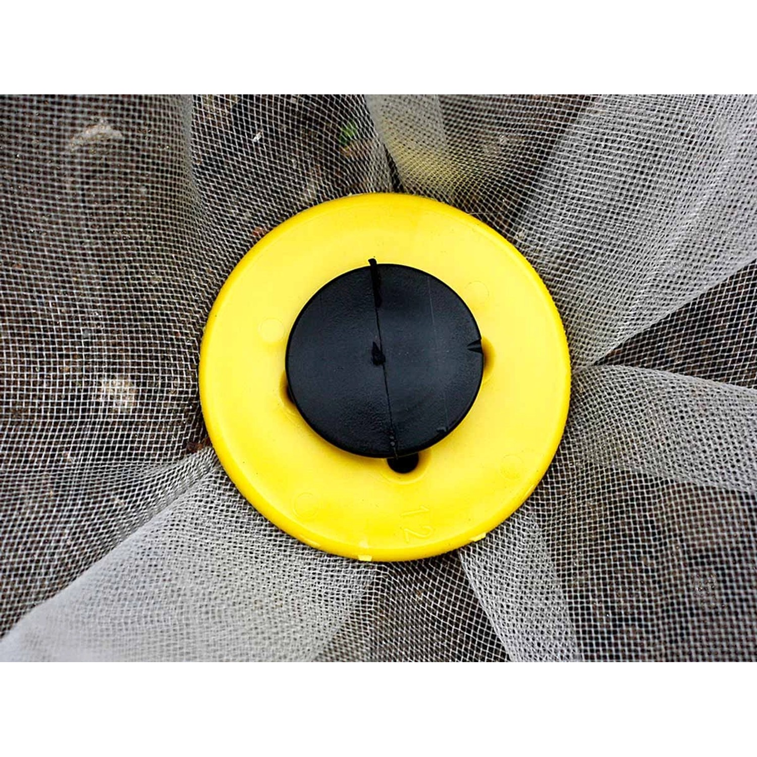 Erdnagel mit gelber Scheibe und schwarzem Kopf zur Vliesbefestigung im Garten.