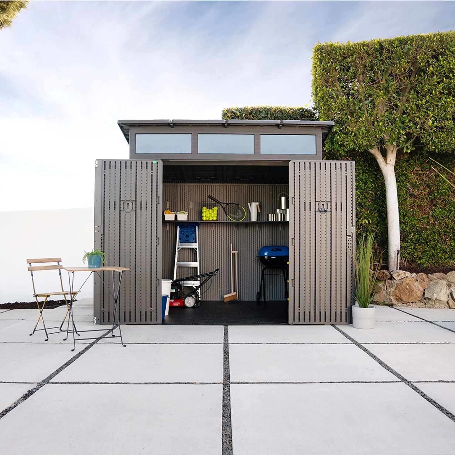 Offenes, dunkelgraues Lifetime Gerätehaus Merkur (5,4 m²) mit Gartengeräten und Möbeln.