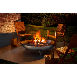 Buschbeck Feuerschale Eisen 120 cm mit brennendem Holz und Gartenmöbeln.