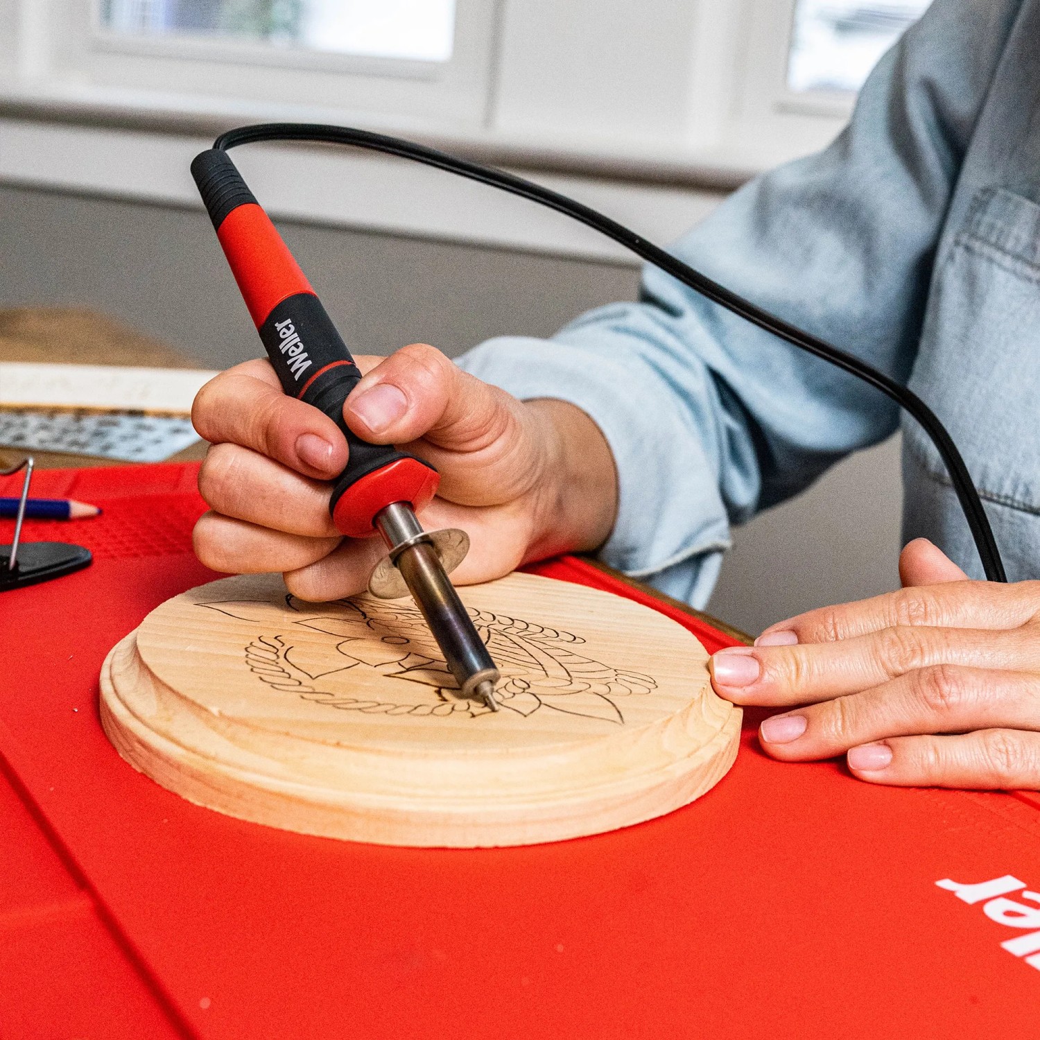 Weller Brandmalerei-Set in Nutzung: Detailaufnahme des Werkzeugs beim Verzieren eines Holzstücks.
