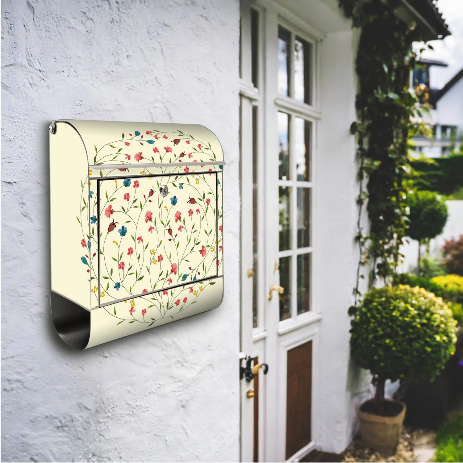 Edelstahl Briefkasten mit Blumenreigen Motiv und Zeitungsfach, montiert an einer weißen Hauswand.