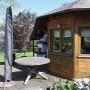 Schwarze Perel Schutzhülle für Sonnenschirm auf Holzterrasse neben Gartenhaus. Optimaler Schutz.