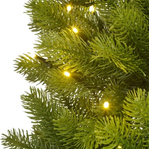 Nahaufnahme einer grünen Kunsttanne mit leuchtenden warmweißen LEDs. Dichte Nadeln des künstlichen Weihnachtsbaums.