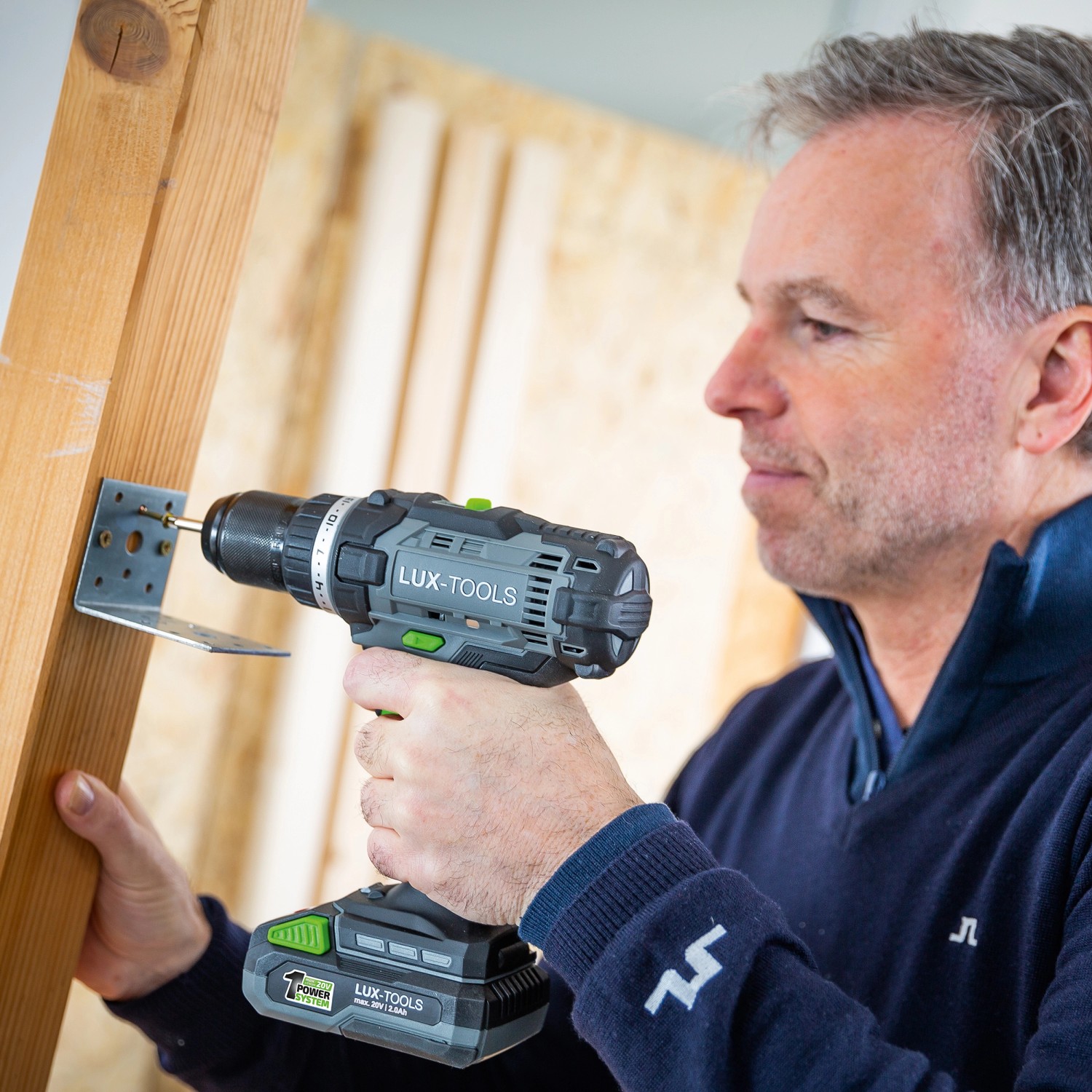 Mann schraubt mit LUX Akku-Bohrschrauber A-BS-20 ein Winkelblech an Holz.