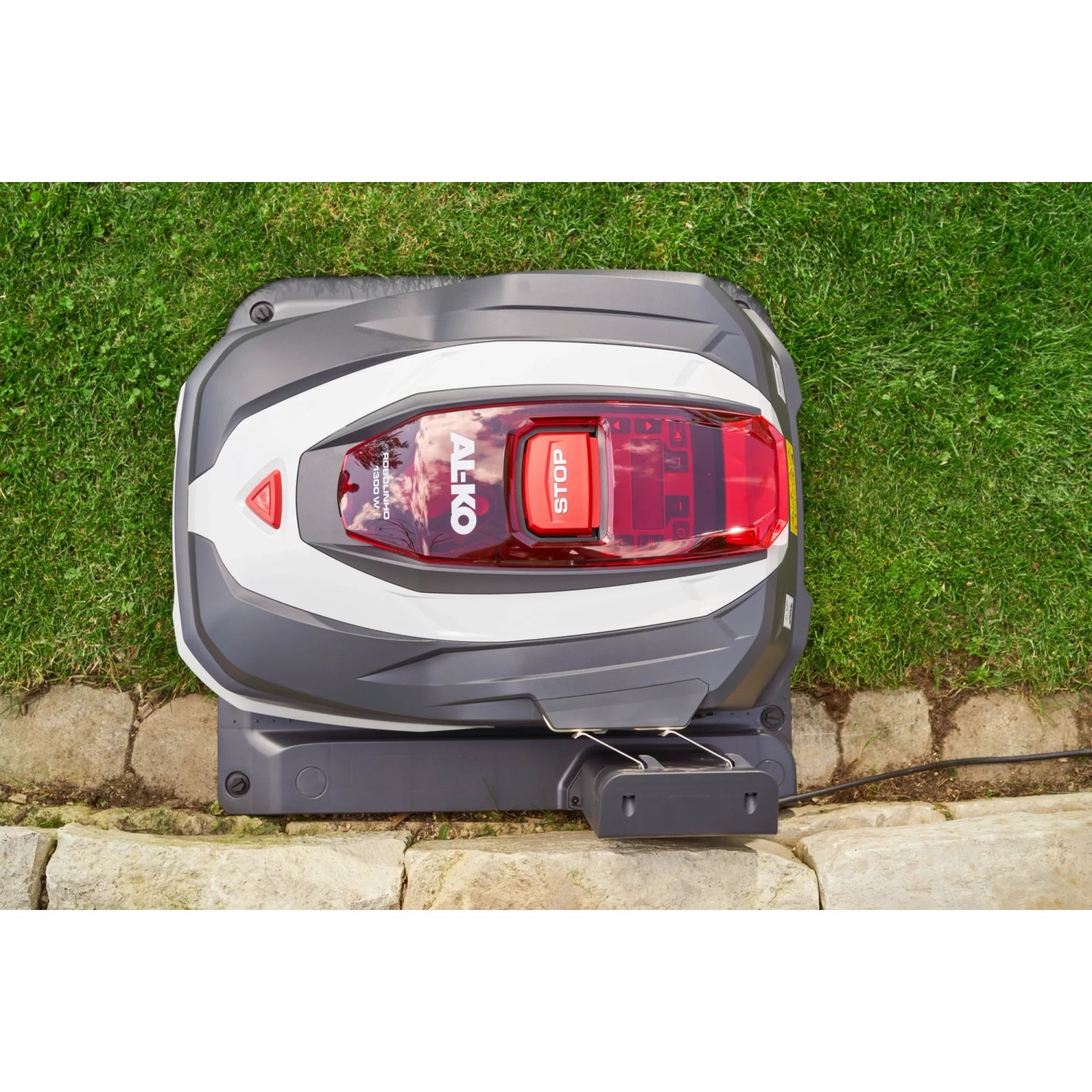 Al-Ko Robolinho 1.300 W Mähroboter auf Rasen, grau-weiß mit rotem Stoppknopf.