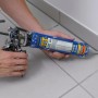 Hände dichten mit Soudal Sanitär Silikon Grau eine Fuge zwischen hellgrauen Fliesen und weißer Wand ab.
