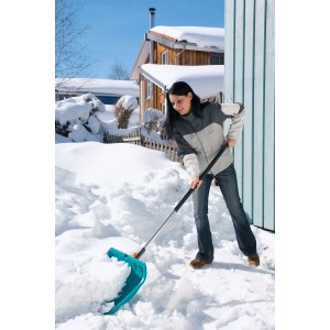 Frau schiebt Schnee mit dem Gardena combisystem Schneeschieber KST 50 cm.