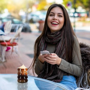Relaxdays gewelltes Trinkglas mit Getränk auf Glastisch im Café. Lachende Frau.