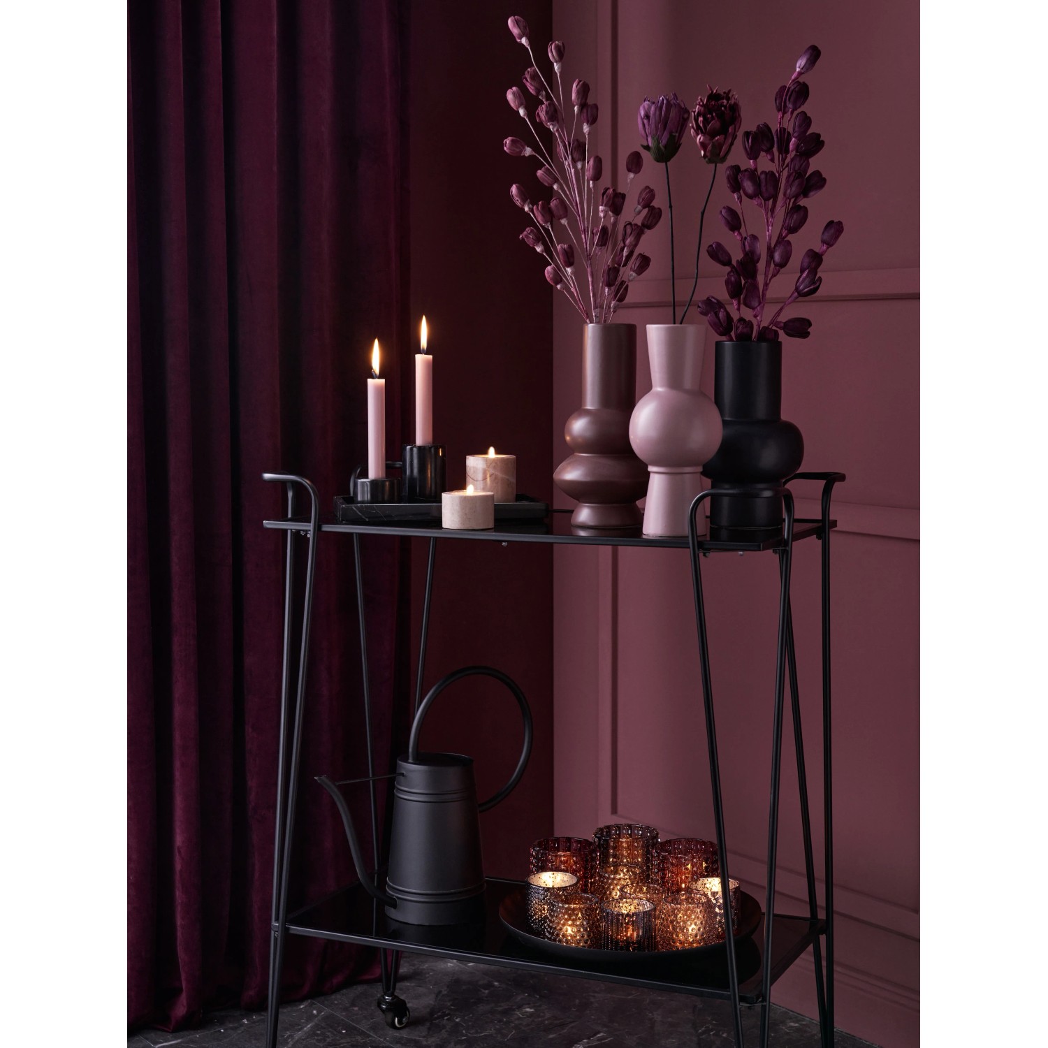 Dekorative schwarze Vase Midnight Mystery auf einem Servierwagen mit Kerzen und Teelichtern.