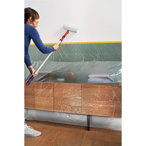 Frau streicht Wand mit Tesa Abdeckfolie Easy Cover Perfect+ L, Möbel abgedeckt.