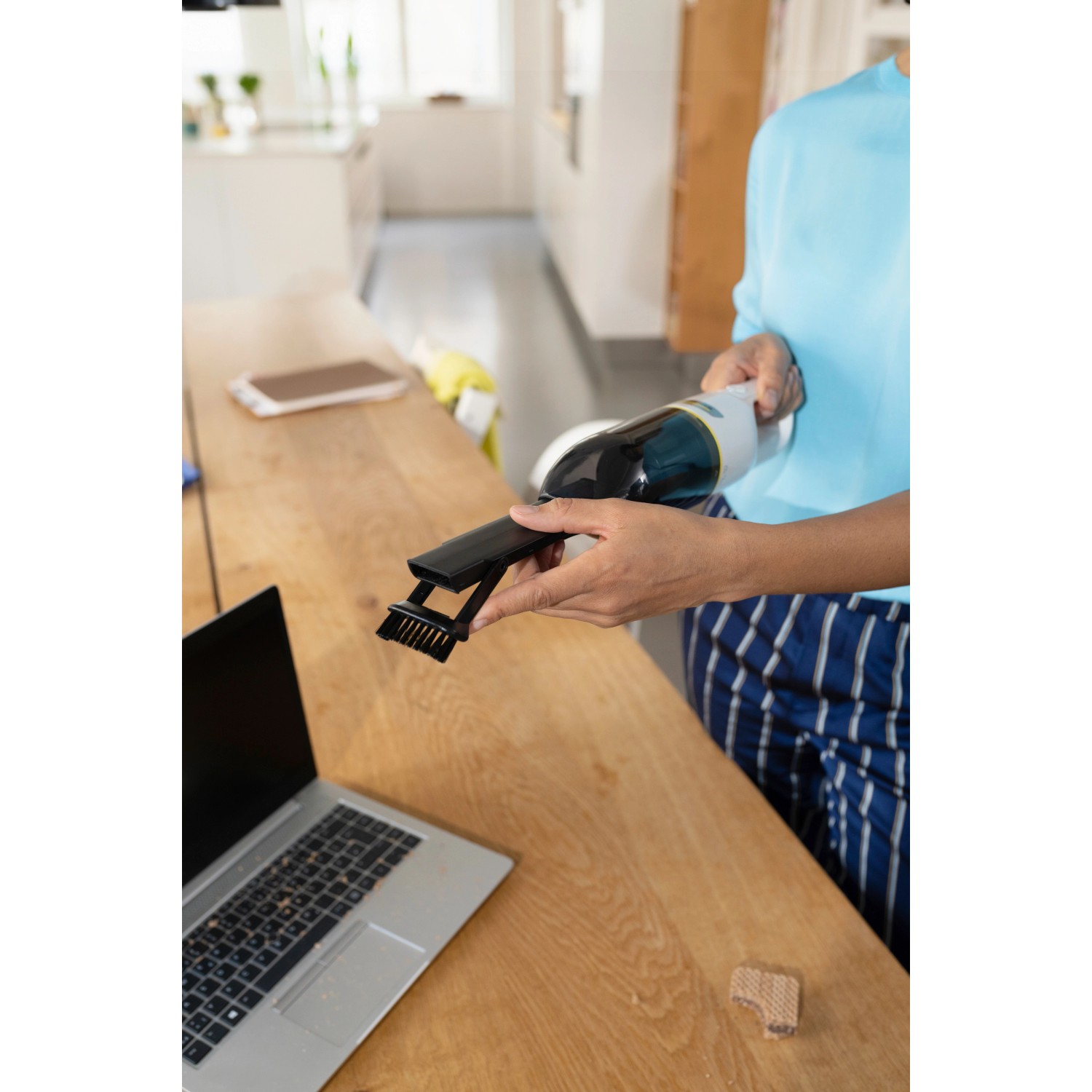 Kärcher Akku-Handstaubsauger CVH 2 im Einsatz mit Bürste zum Reinigen eines Tisches.