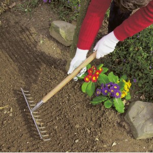 Person mit LUX Feinstrick-Handschuhen Gr. 7 beim Harken im Garten.