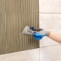 Auftragen von Knauf Flexkleber Naturstein mit Zahnspachtel auf Fliesen.