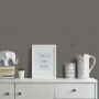 Erismann Vliestapete Spotlight Uni Schwarz an Wand über Kommode mit Deko.