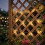 Warmweiße LED Solar Feuerwerk Lichterkette am Holzspalier. Garten-Deko für stimmungsvolle Weihnachtsbeleuchtung.