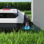 Ecovacs Goat A3000 Mähroboter beim Kantenschneiden nahe einer Mauer.