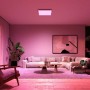 Philips Hue Surimu Panel in Weiß und Farbe, 60x60 cm, in modernem Wohnzimmer mit farbiger Beleuchtung.