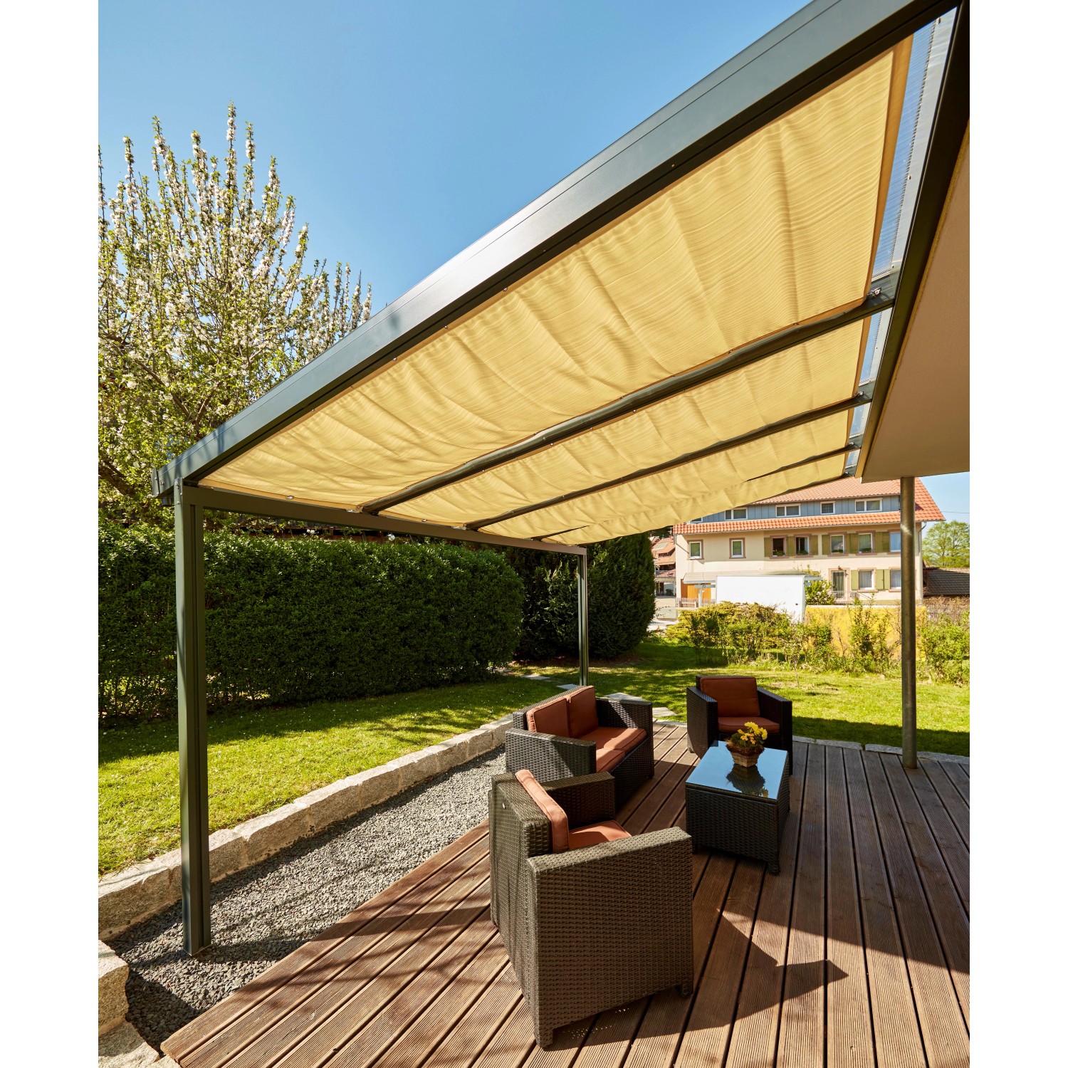 Gutta Seilspannmarkise Sandstone auf Terrasse mit Gartenmöbeln. Sonnenschutz für Terrassenüberdachungen.