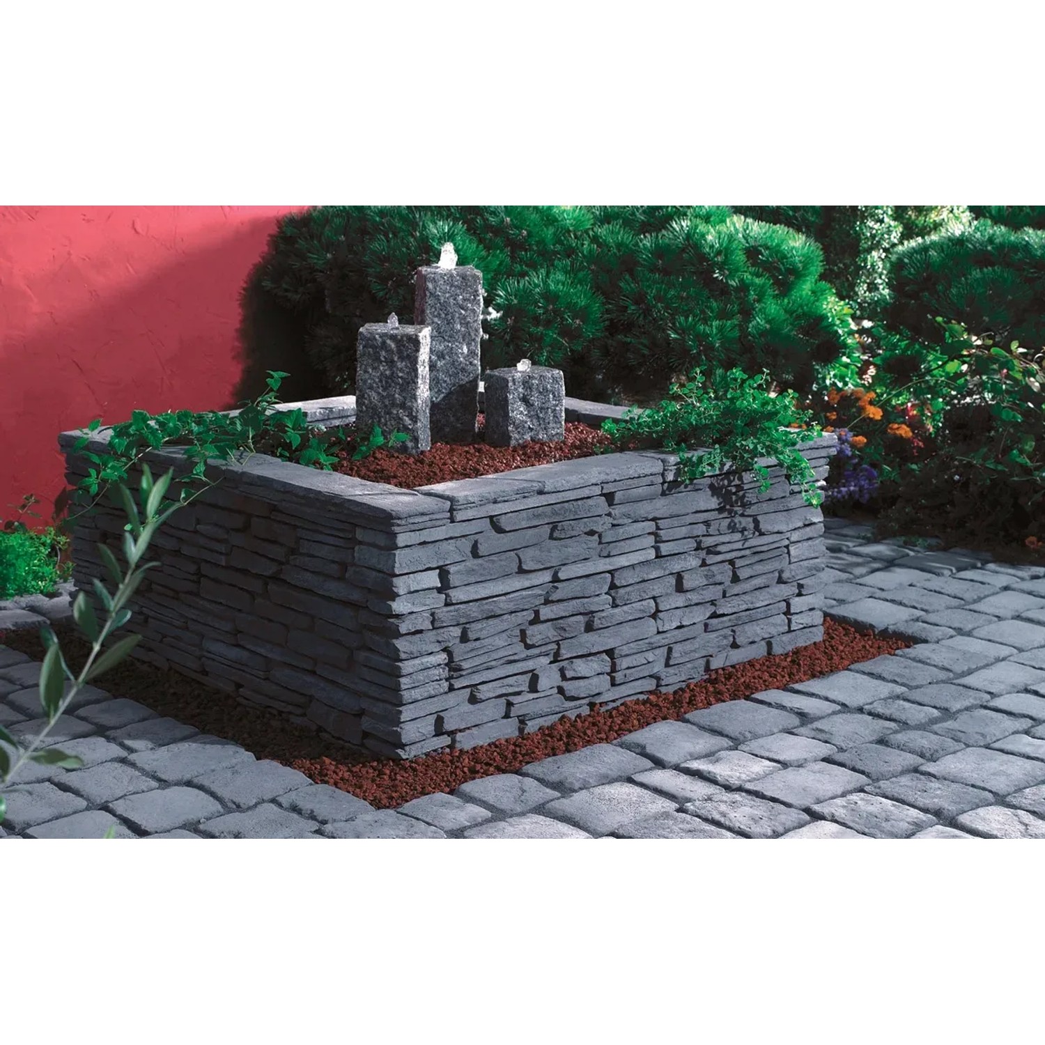 Ziermauer Madoc Schiefergrau mit Wasserfall und Bepflanzung im Garten.