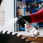 Person sprüht Ballistol Harzlöser Pumpspray auf Sägeblatt zur Werkzeugreinigung. Entfernt Harzrückstände effektiv.