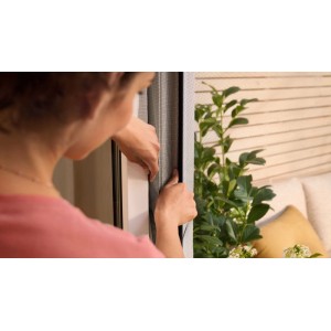 Montage des weißen tesa® Insect Stop Fliegengitters am Fensterrahmen.