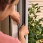 Montage des weißen tesa® Insect Stop Fliegengitters am Fensterrahmen.