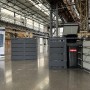 Mülltonnenbox für 4 Mülltonnen aus anthrazitfarbenem verzinktem Stahl, robust und wetterfest. Eine Tür ist geöffnet.