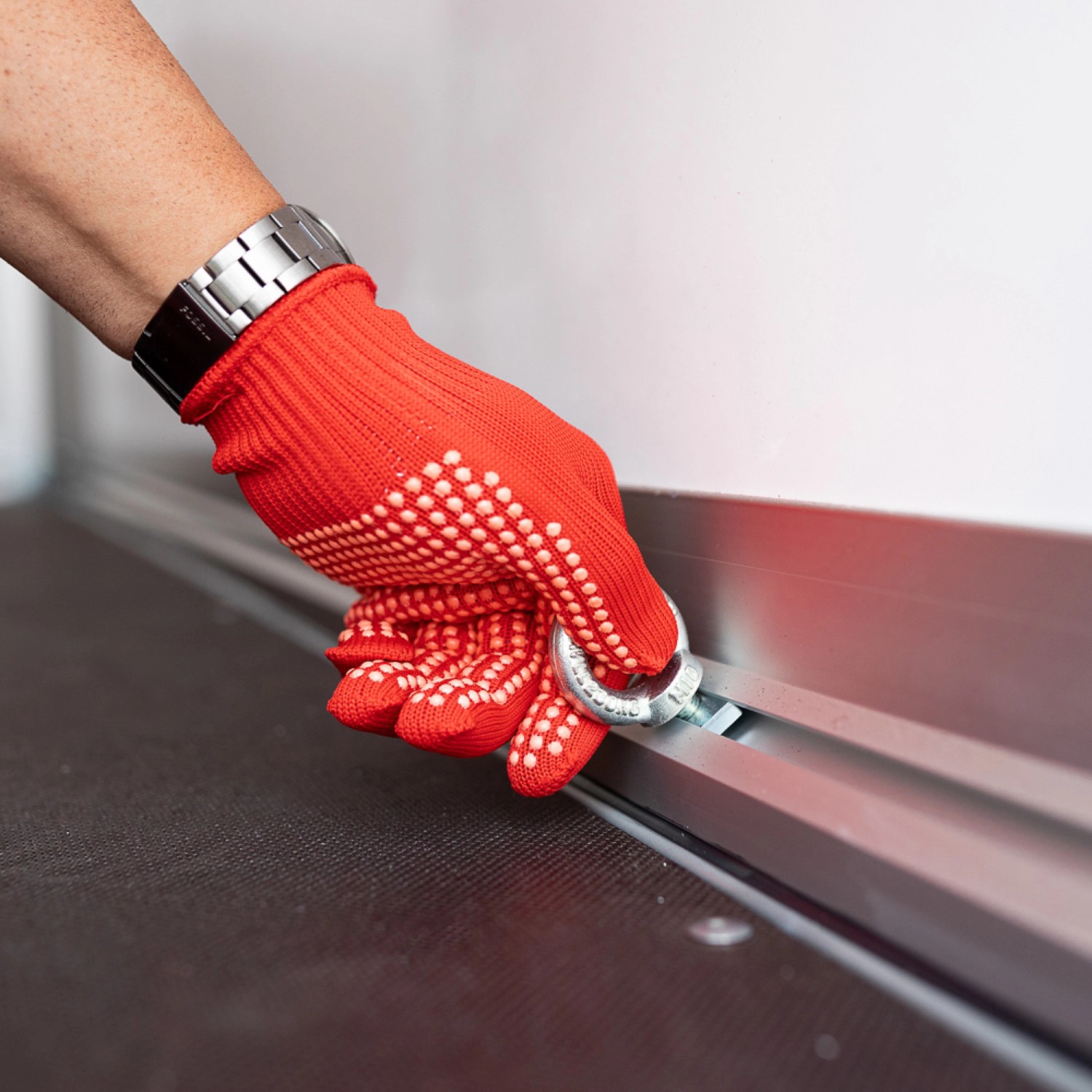 Detailaufnahme: Hand mit rotem Handschuh befestigt Zurröse im Stema Kofferanhänger 1300 Sandwich.