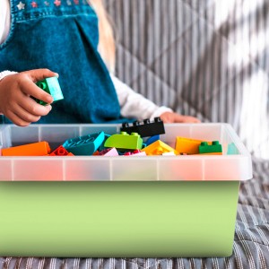 Pistazienfarbene Venilia Klebefolie (45x200cm) mit Spielzeugsteinen in transparenter Box.