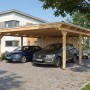 Großer Holz-Carport mit Flachdach und Abstellraum, schützt zwei Fahrzeuge. Naturholz-Konstruktion vor Haus.