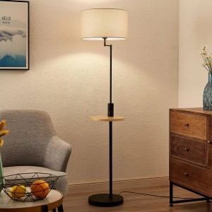 Moderne Lindby Stehlampe Zinia schwarz aus Metall mit hellem Textilschirm, Holzablage und USB-Anschluss im Wohnzimmer.