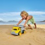 Kind spielt mit gelbem Hape Sandlaster am Strand. Robustes Spielzeug für Sandkasten und mehr.