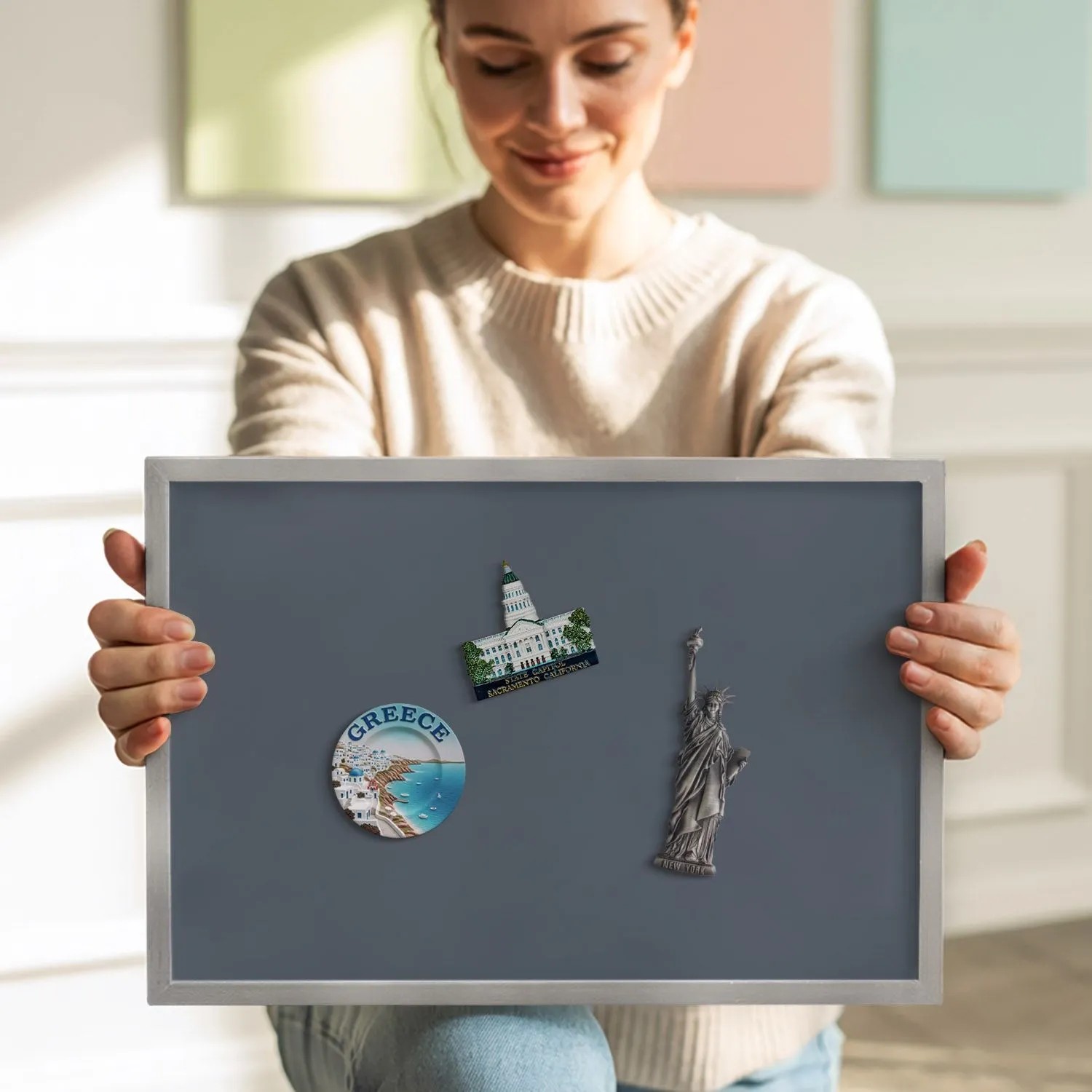 Graue Tulup Magnettafel 100x70 cm mit silbernem Rahmen, von einer Person gehalten. Ideal für Reisemagnete und Notizen.