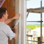 Mann verklebt Fensterrahmen mit Siga Fentrim 20 Klebeband für luftdichte Dämmung.
