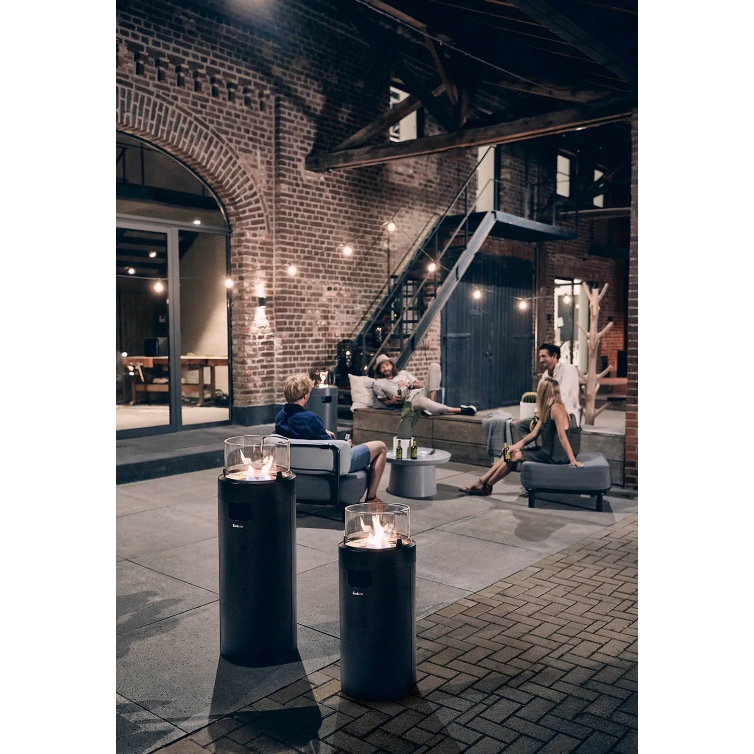Enders® Feuerstelle Nova LED M Black-Chrome im Außenbereich mit Glaszylinder und Ambientebeleuchtung.