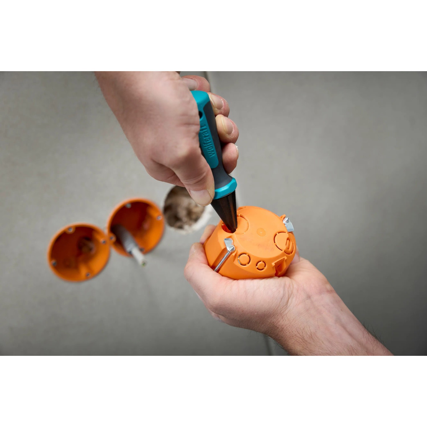 Wolfcraft Handlochfräser Ergo im Einsatz an einer orangefarbenen Verteilerdose.