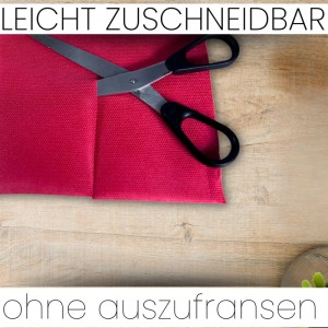 Pinke Sensalux Vlies-Tischdecke wird mit einer Schere zugeschnitten.
