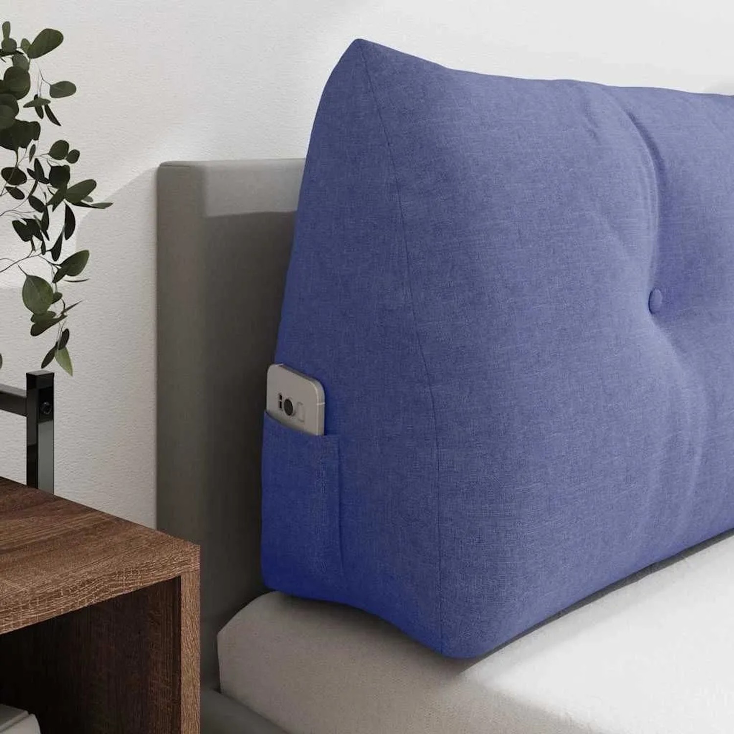 Jeans blaues Rückenkissen aus Stoff mit Knopfheftung und Seitentasche, auf einem Bett. Bietet ergonomischen Komfort.