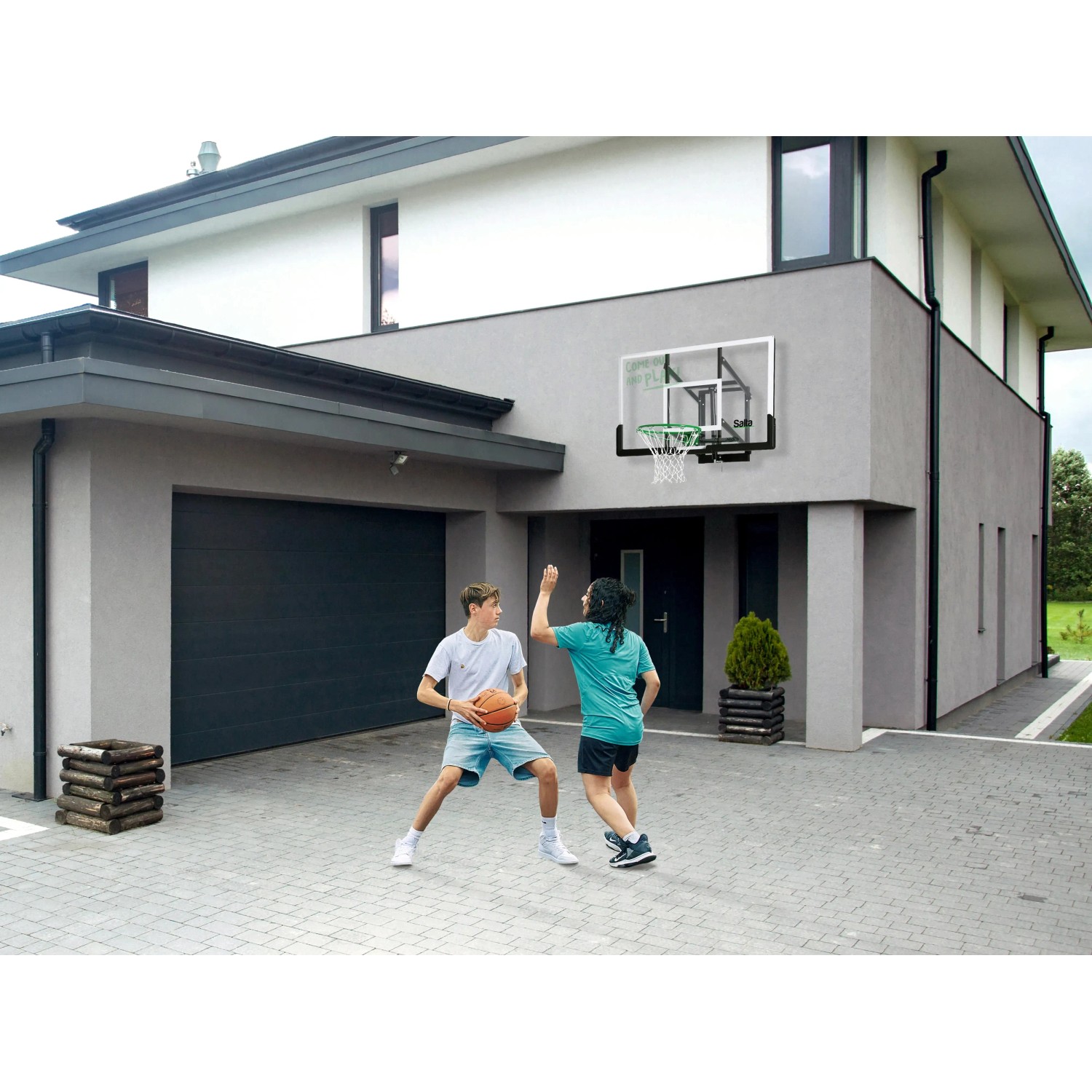 Salta Basketballbrett Center mit zwei spielenden Personen vor Hauswand.