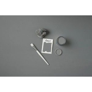 Rust-Oleum Kreidefarbe Anthrazit mit Pinsel, Farbmuster und Stein auf grauem Grund.