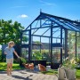 Juliana Gewächshaus Premium 10 Anthrazit mit Kind, Hühnern und Pflanzen im Garten.