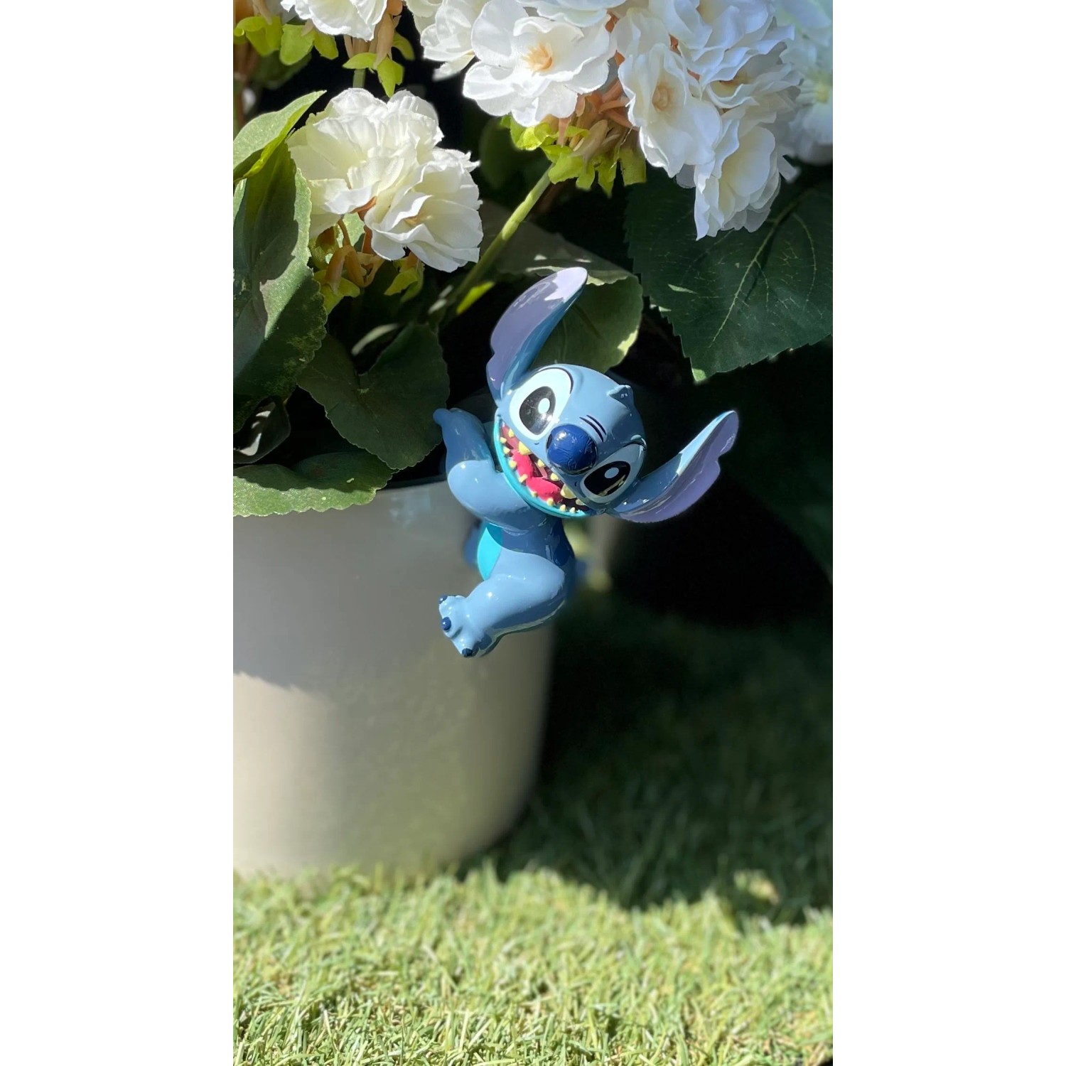 Blauer Stitch Topfanhänger als Deko-Figur am Blumentopf im Garten.