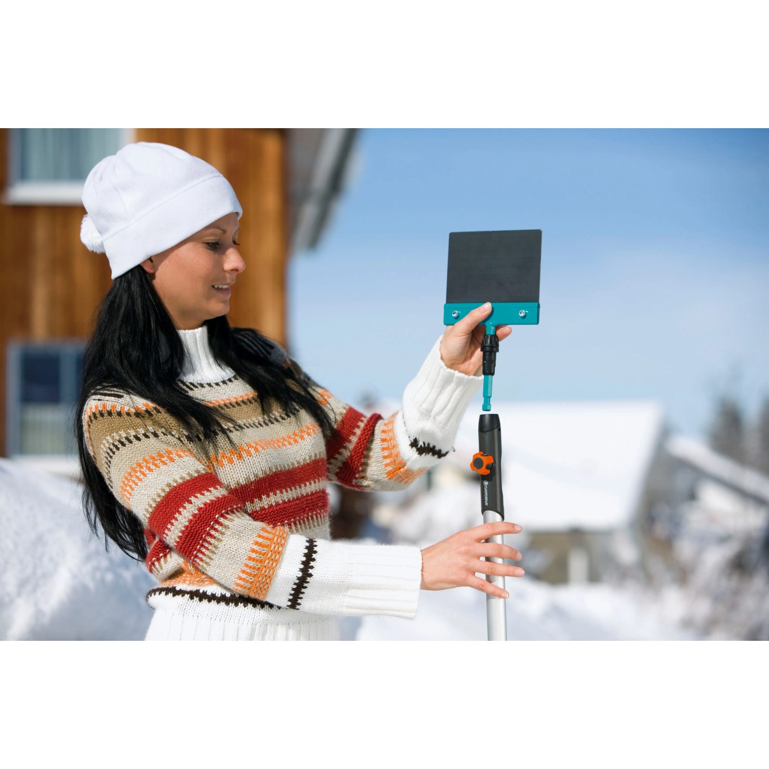 Frau montiert Gardena combisystem Stoßscharre 15 cm am Stiel im Winter.