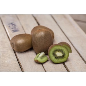 Frische, braune Kiwis, angeschnitten, auf hellem Holz. GROW by OBI Kiwi Solo.