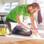 Mann verlegt Parkett mit Soudal Parkettkleber 68A 5 kg. Kleber und Werkzeug im Bild.
